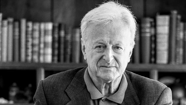 Ein Mann mit grauen Haaren blickt in die Kamera. Hinter ihm ein Buchregal. Ein Mann mit grauen Haaren blickt in die Kamera. Hinter ihm ein Buchregal.