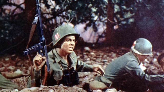 Zwei Soldaten in Uniform und mit Helm im Schützengraben, der eine kehrt der Kamera den Rücken zu, der andere hält sein Gewehr in die Höhe Zwei Soldaten in Uniform und mit Helm im Schützengraben, der eine kehrt der Kamera den Rücken zu, der andere hält sein Gewehr in die Höhe