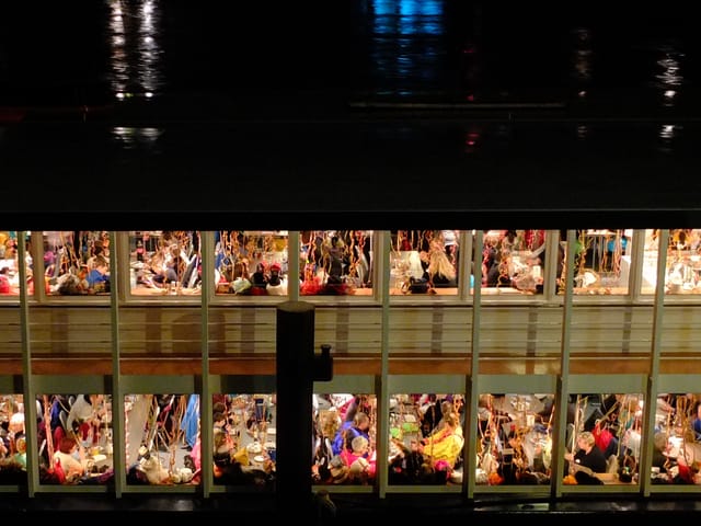 Beleuchtete Fenster des Fasnachtsschiffs, dahinter Gäste.