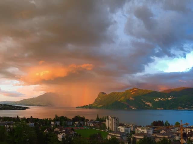 Über dem Urnersee steht ein Vorhang aus starkem Regen. Dieser wird von der Abendsonne golden beleuchtet.