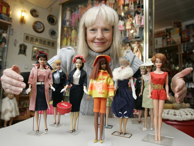 Eine blonde Frau hält ihre lieblingsbarbies vor die Kamera Eine blonde Frau hält ihre lieblingsbarbies vor die Kamera