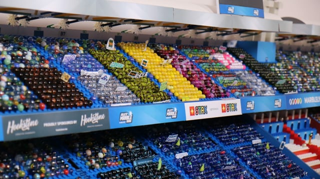 Tribüne in einem Modell-Sportstadion. Auf den Sitzplätzen sind bunte Murmeln aus Glas platziert. Tribüne in einem Modell-Sportstadion. Auf den Sitzplätzen sind bunte Murmeln aus Glas platziert.
