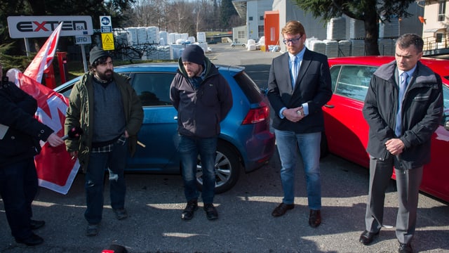 Streikende und Unternehmensvertreter vor zwei Autos im Gespräch Streikende und Unternehmensvertreter vor zwei Autos im Gespräch