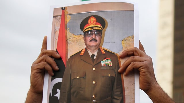 Jemand hält ein Bild von Haftar in die Luft. Jemand hält ein Bild von Haftar in die Luft.