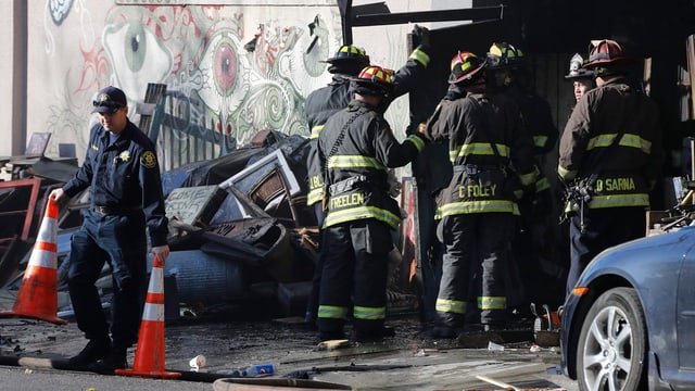 Feuerwehrleute vor einer verkohlten Hauswand. Feuerwehrleute vor einer verkohlten Hauswand.