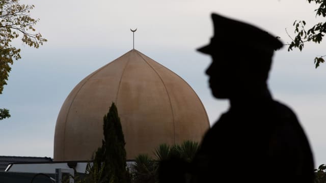 EIn Polizist vor der Kuppel einer Moschee EIn Polizist vor der Kuppel einer Moschee