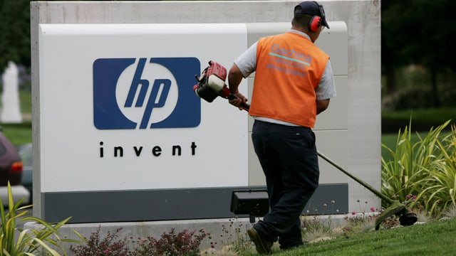 Angestellter mäht vor dem Firmenschild von HP den Rasen Angestellter mäht vor dem Firmenschild von HP den Rasen