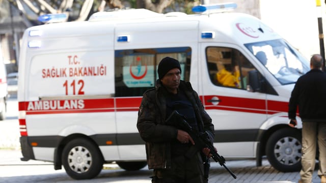 Ein bewaffneter Polizist vor einem Ambulanz-Wagen Ein bewaffneter Polizist vor einem Ambulanz-Wagen