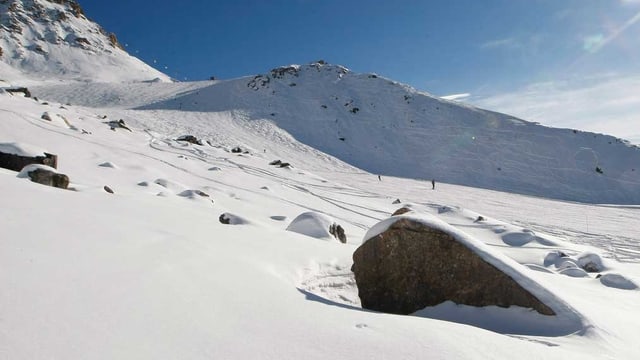 Ein grosser Fels steht am Rande einer sonnigen Skipiste. Ein grosser Fels steht am Rande einer sonnigen Skipiste.