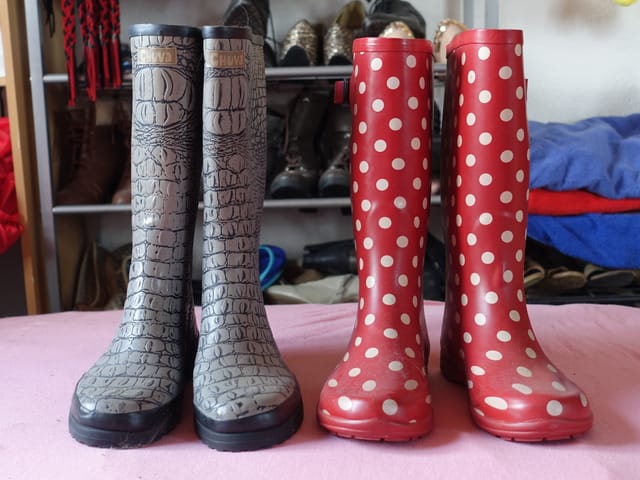 Zwei Paar Gummistiefel, rechts rot mit weissen Punkten, links in Lederoptik Zwei Paar Gummistiefel, rechts rot mit weissen Punkten, links in Lederoptik