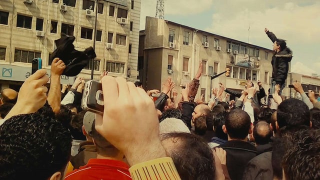 Filmszene: Eine Menschenmenge, vilee strecken die Arme in die Luft Filmszene: Eine Menschenmenge, vilee strecken die Arme in die Luft