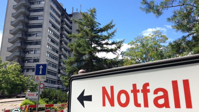 Schild mit Aufschrift Notfall neben Spital-Hochhaus Schild mit Aufschrift Notfall neben Spital-Hochhaus