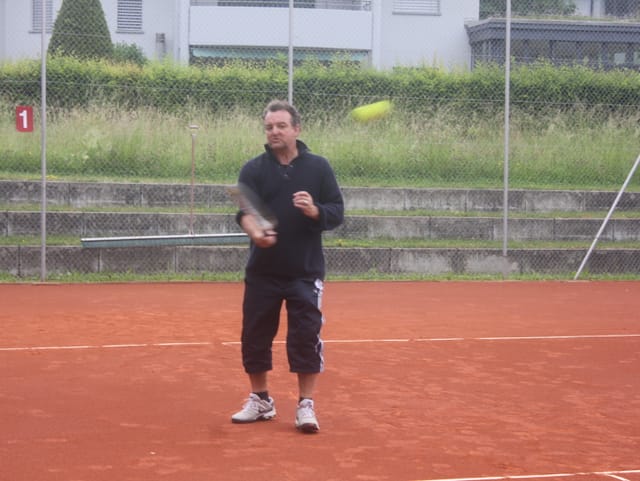 Marco Rima steht auf dem Tennisplatz und spielt einen Ball.