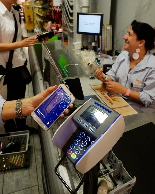 Ein Kunde zahlt im Supermarkt an der Kasse mit einer Handy-App. Ein Kunde zahlt im Supermarkt an der Kasse mit einer Handy-App.