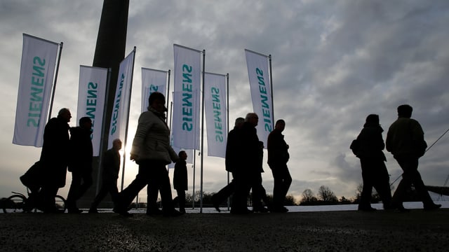 Leute vor Siemensflaggen bei bedecktem Himmel. Leute vor Siemensflaggen bei bedecktem Himmel.