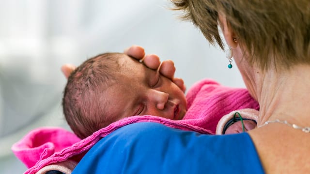 Ein Neugeborenes auf dem Arm einer Pflegerin im Universitätsspital Zürich