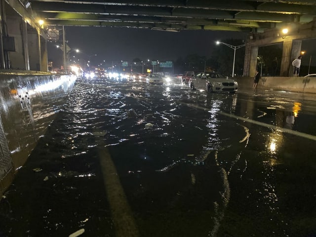 People stand under an underpass while their cars stall on the Long Island Expressway.
