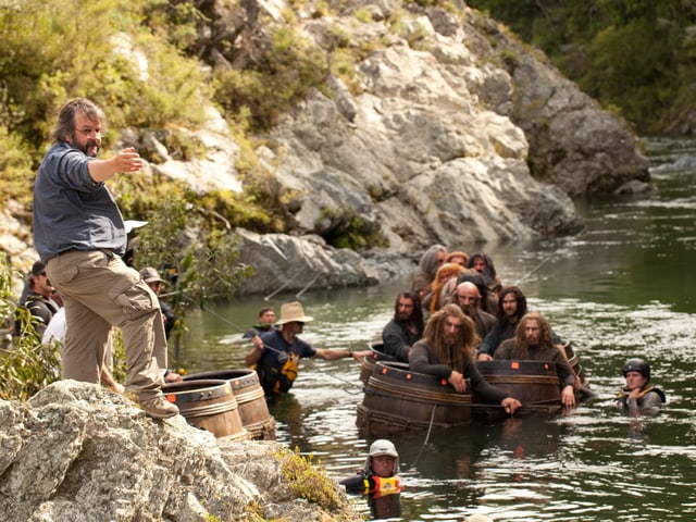 Foto vom Dreh: In einem Fluss sitzen Zwerge in Holzfässern, am Ufer steht Peter Jackson. Foto vom Dreh: In einem Fluss sitzen Zwerge in Holzfässern, am Ufer steht Peter Jackson.
