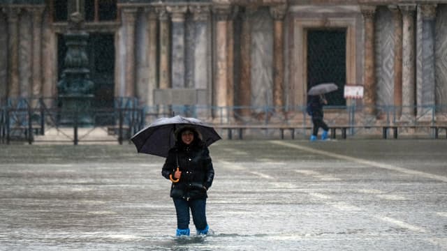 Frau mit Regenschirm im Hochwasser auf dem Markusplatz.