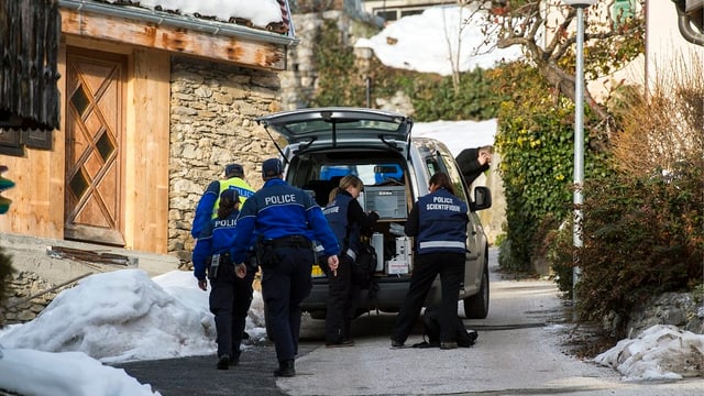 Walliser Kantonspolizisten hinter einem Fahrzeug in enger Gasse Walliser Kantonspolizisten hinter einem Fahrzeug in enger Gasse