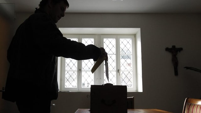 Ein Mann im Gegenlicht wirft seinen Stimmzettel in eine Urne. Ein Mann im Gegenlicht wirft seinen Stimmzettel in eine Urne.