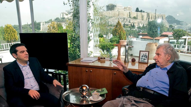 Alexis Tsipras spricht mit Mikis Theodorakis, der in eine Decke gehüllt ist. Alexis Tsipras spricht mit Mikis Theodorakis, der in eine Decke gehüllt ist.
