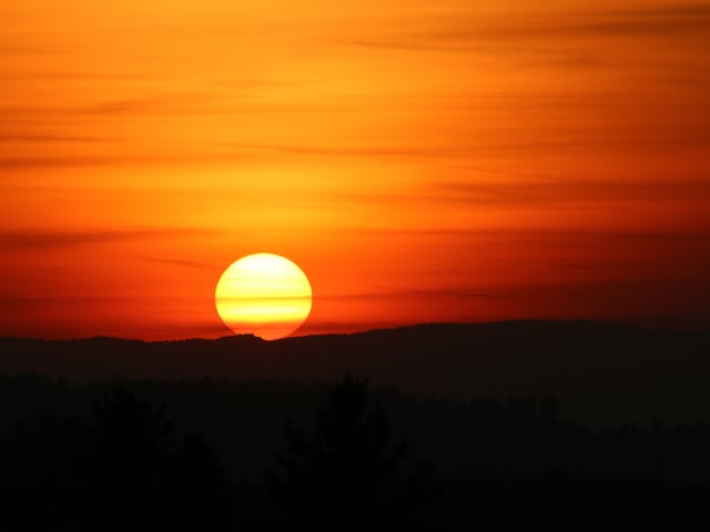 Organge-roter Himmel, die Landschaft bis zum Horizont nur noch in schwart.