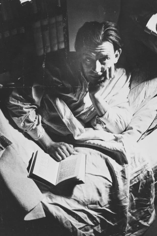 Friedrich Glauser liegt auf dem Bett mit einem Buch. Er stützt seinen Kopf. Friedrich Glauser liegt auf dem Bett mit einem Buch. Er stützt seinen Kopf.