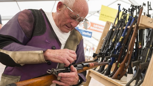 Mann mit Gewehr vor Gewehrständer Mann mit Gewehr vor Gewehrständer