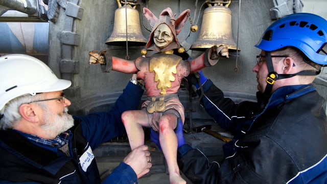 Zwei Arbeiter mit Helm nehmen die Figur ab der berühmten Turm-Uhr. Zwei Arbeiter mit Helm nehmen die Figur ab der berühmten Turm-Uhr.