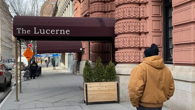 Ein Mann, Arme in den Hosentaschen, geht vor dem Eingang zum Hotel Lucerne