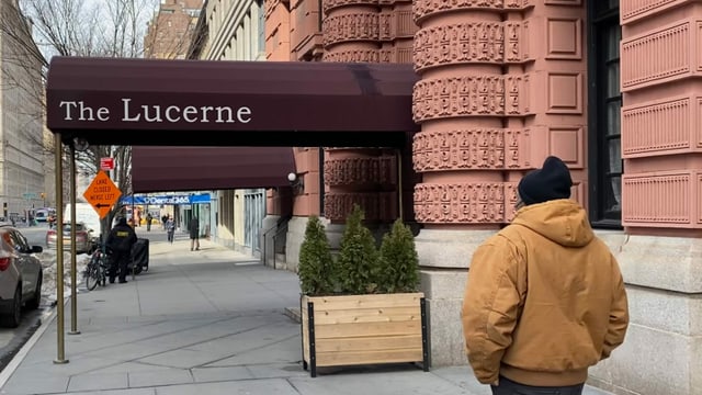 Ein Mann, Arme in den Hosentaschen, geht vor dem Eingang zum Hotel Lucerne Ein Mann, Arme in den Hosentaschen, geht vor dem Eingang zum Hotel Lucerne