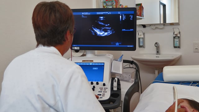Ärztin untersucht mit Ultraschall ein Kleinkind