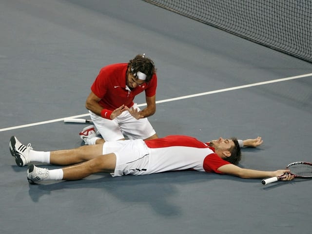 Roger Federer wärmt sich symbolhaft seine Hände am brennenden Stan Wawrinka. Roger Federer wärmt sich symbolhaft seine Hände am brennenden Stan Wawrinka.