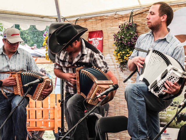Drei Männer spielen Ziehharmonika.