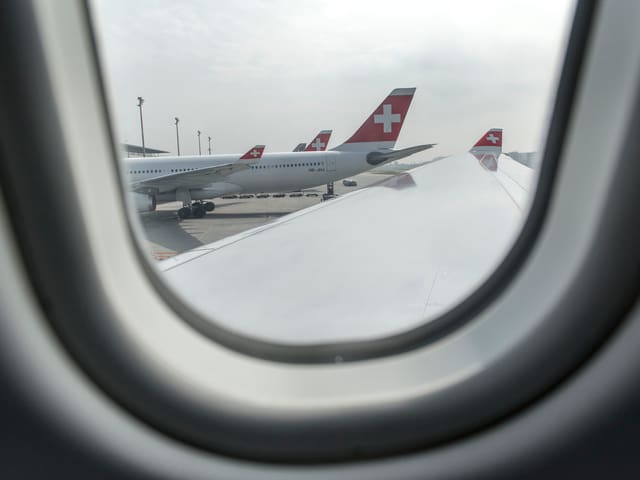 Blick durch ein Flugzeugfenster auf Swiss-Flugzeuge. Blick durch ein Flugzeugfenster auf Swiss-Flugzeuge.