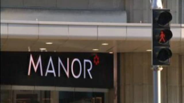 Manor-Schriftzug mit roter Ampel Manor-Schriftzug mit roter Ampel