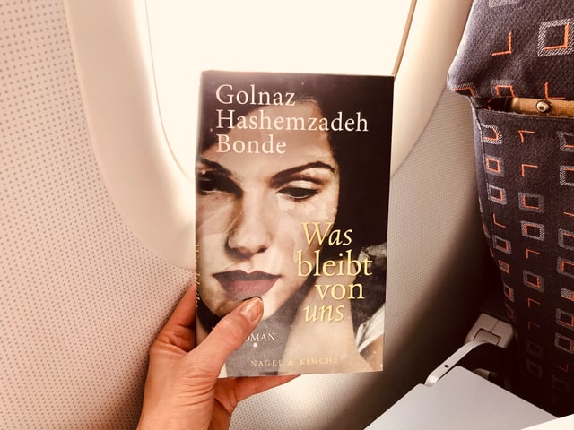 Das Buch von Golnaz Hashemzadeh Bonde: «Was bleibt von uns» vor einem Flugzeugfenster Das Buch von Golnaz Hashemzadeh Bonde: «Was bleibt von uns» vor einem Flugzeugfenster