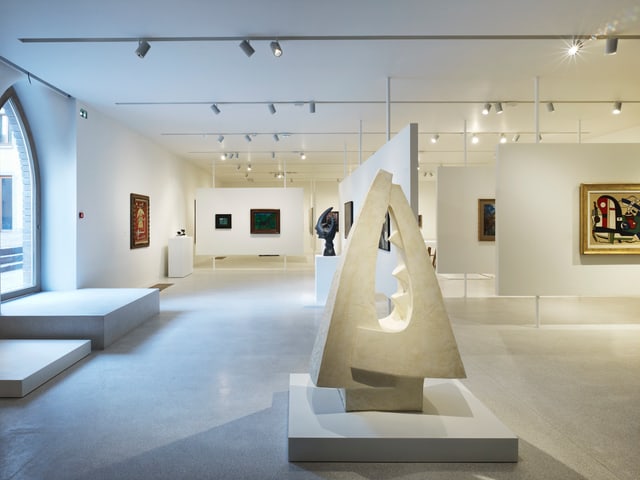 Eine Skulptur und Bilder in einem Ausstellungsraum. Eine Skulptur und Bilder in einem Ausstellungsraum.