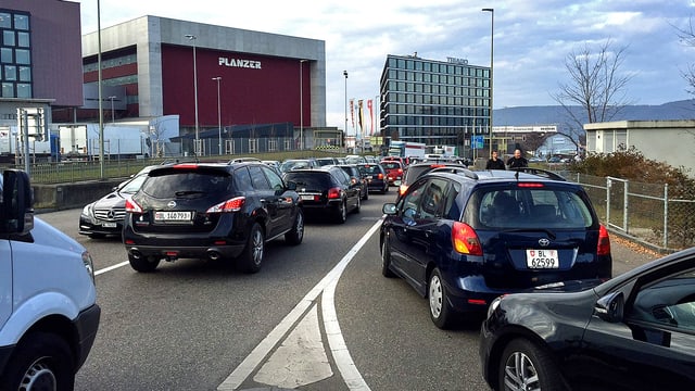 Stehende Autos auf einer Autobahnkreuzung. Im Hintergrund die Gebäude des Gewerbeviertels von Pratteln. Stehende Autos auf einer Autobahnkreuzung. Im Hintergrund die Gebäude des Gewerbeviertels von Pratteln.