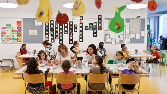 Kinder sitzen in einem Hort zum gemeinsamen Essen am Tisch Kinder sitzen in einem Hort zum gemeinsamen Essen am Tisch