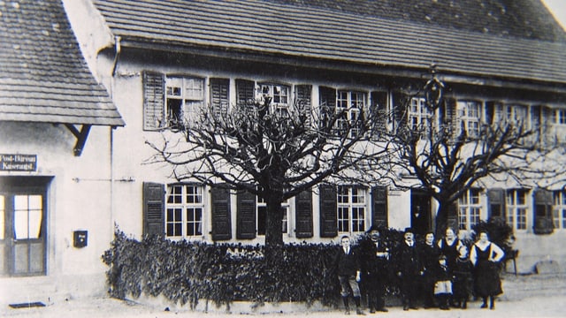 Schwarzweiss-Foto eines Landgasthofes, mit Personen im Vordergrund. Schwarzweiss-Foto eines Landgasthofes, mit Personen im Vordergrund.