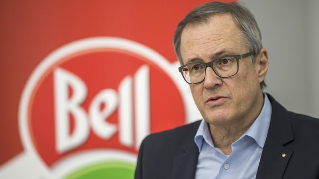 Mann vor rotem Bell Logo Mann vor rotem Bell Logo