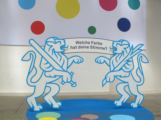 Farbige Punkte als Symbol für die Parteifarben, die Zürcher Wappentiere halten ein Banner mit der Frage: Welche Farbe hat deine Stimme? Farbige Punkte als Symbol für die Parteifarben, die Zürcher Wappentiere halten ein Banner mit der Frage: Welche Farbe hat deine Stimme?