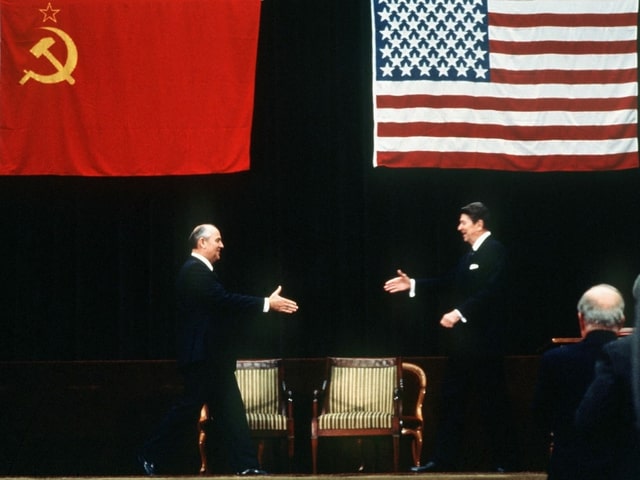 Michail Gorbatschow und Roland Reagan strecken einander die Hand zur Begrüssung hin. Michail Gorbatschow und Roland Reagan strecken einander die Hand zur Begrüssung hin.