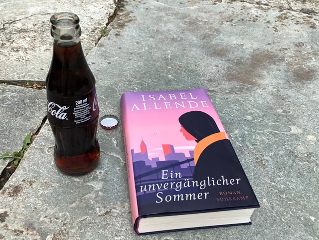 Der Roman «Ein unvergänglicher Sommer» von Isabel Allende liegt auf einem Spaghetti-Liegestuhl, ein Eis-Zitronen-Limonade steht daneben Der Roman «Ein unvergänglicher Sommer» von Isabel Allende liegt auf einem Spaghetti-Liegestuhl, ein Eis-Zitronen-Limonade steht daneben