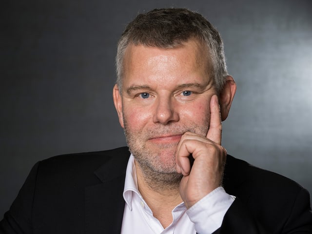 Ein Mann hält seine Hand an seine Wange und lächelt. Ein Mann hält seine Hand an seine Wange und lächelt.