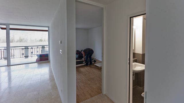 Ein Mann räumt eine leere Neubauwohnung ein. Ein Mann räumt eine leere Neubauwohnung ein.