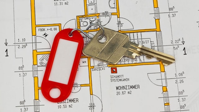 Ein Wohnungsschlüssel mit rotem Anhänger liegt auf einem Wohnungsplan. Ein Wohnungsschlüssel mit rotem Anhänger liegt auf einem Wohnungsplan.