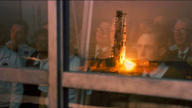 Rakete startet. Menschen spiegeln sich im Fenster, durch welches sie den Start beobachten. Rakete startet. Menschen spiegeln sich im Fenster, durch welches sie den Start beobachten.